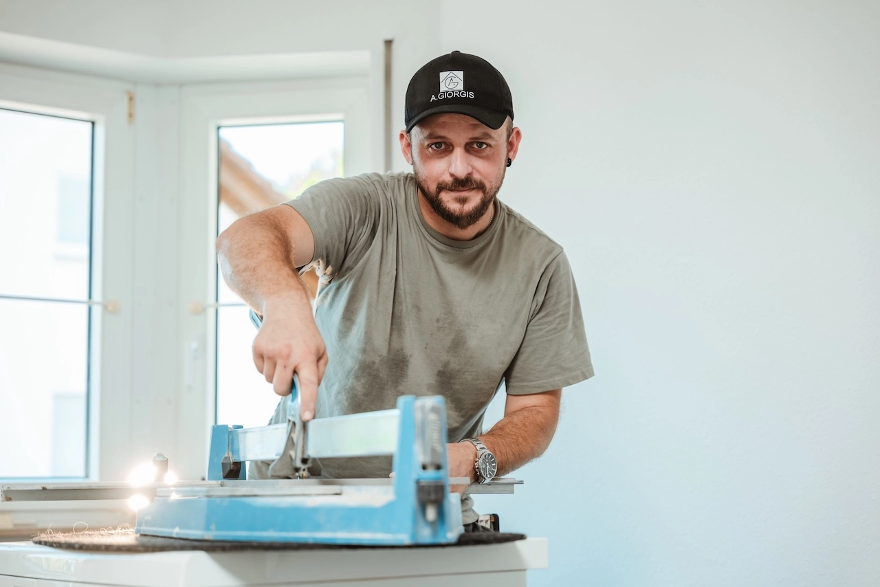 Thomas Nikollas von Alexandros Giorgis bei einer Badsanierung in Freiburg am Fliesen Schneiden