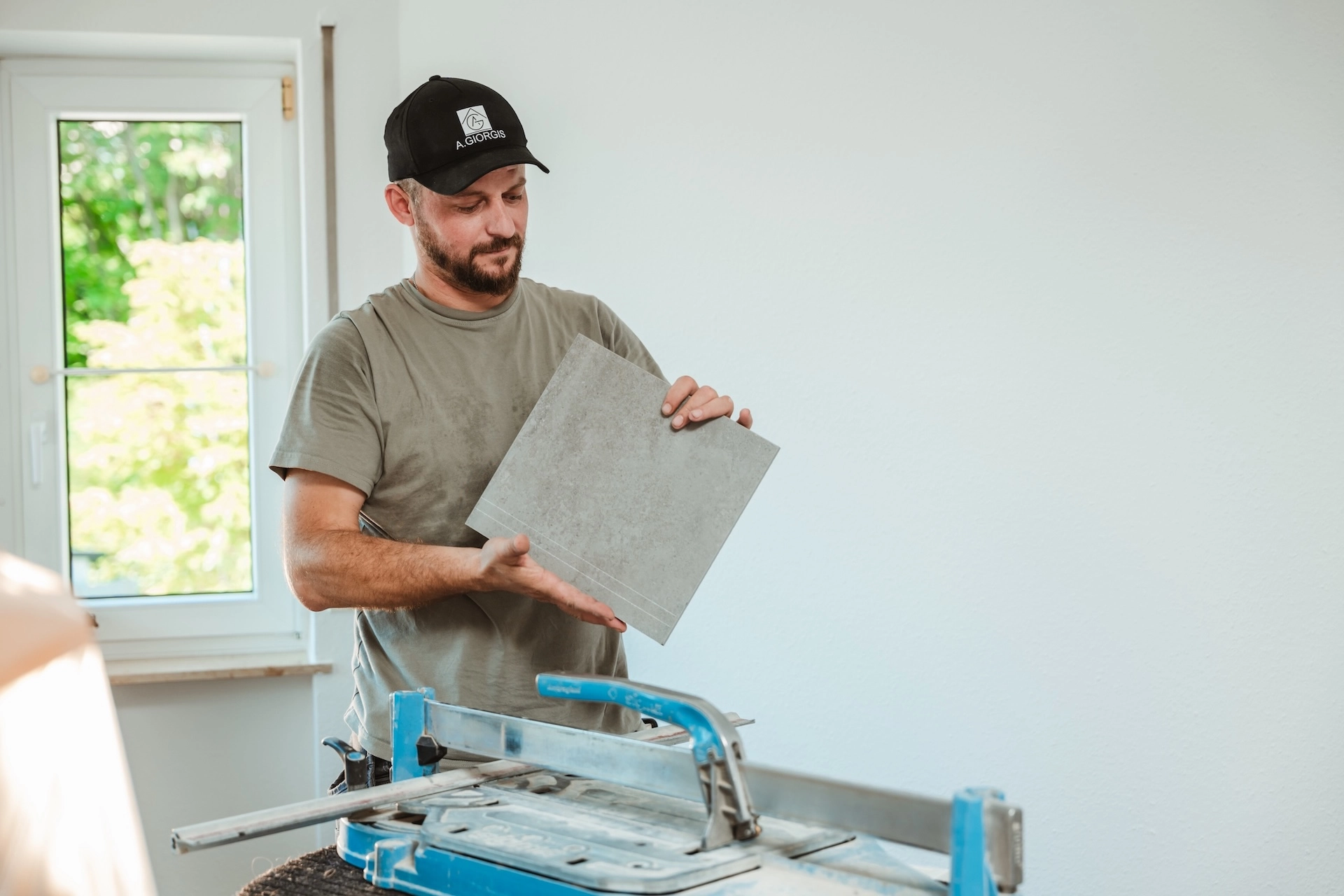 Thomas Nikollas von Alexandros Giorgis bei einer Badsanierung in Freiburg am Fliesen Schneiden